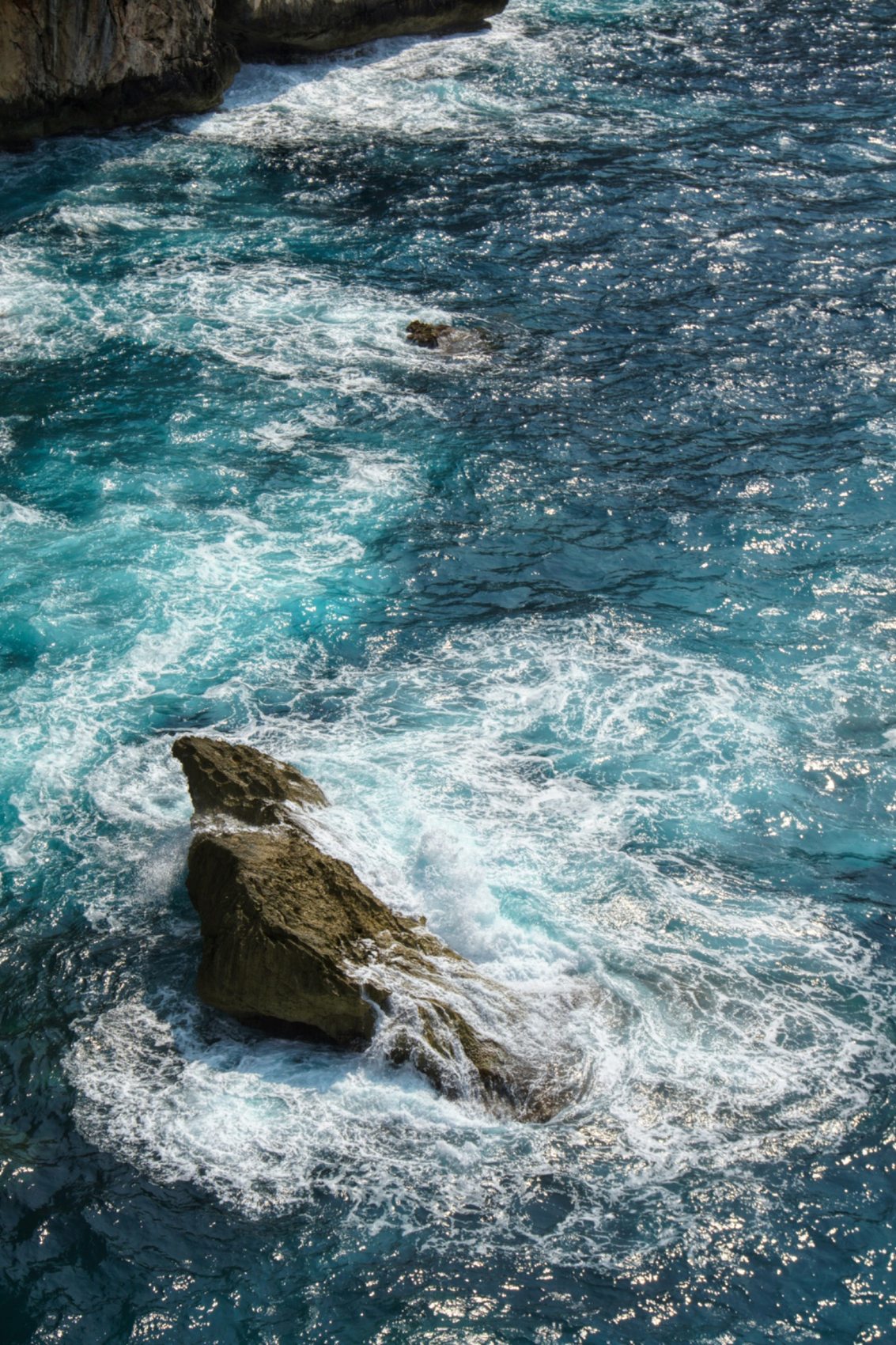 岩を囲む青い海と白い波